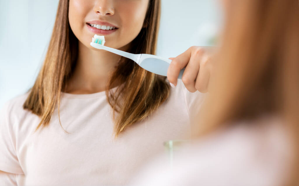Teenager-Mädchen mit elektrischer Zahnbürste beim Zähneputzen - Foto, Bild
