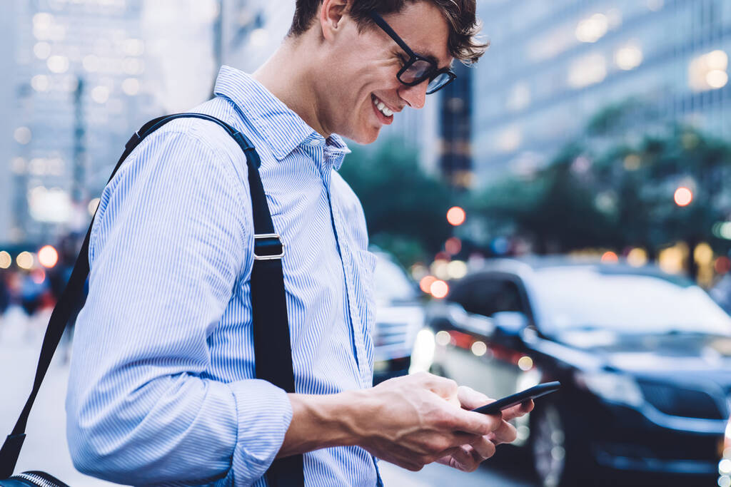 ニューヨークの笑顔を背景に電話でチャットバッグ付きシャツや眼鏡で男性従業員のミステリーサイドビュー - 写真・画像