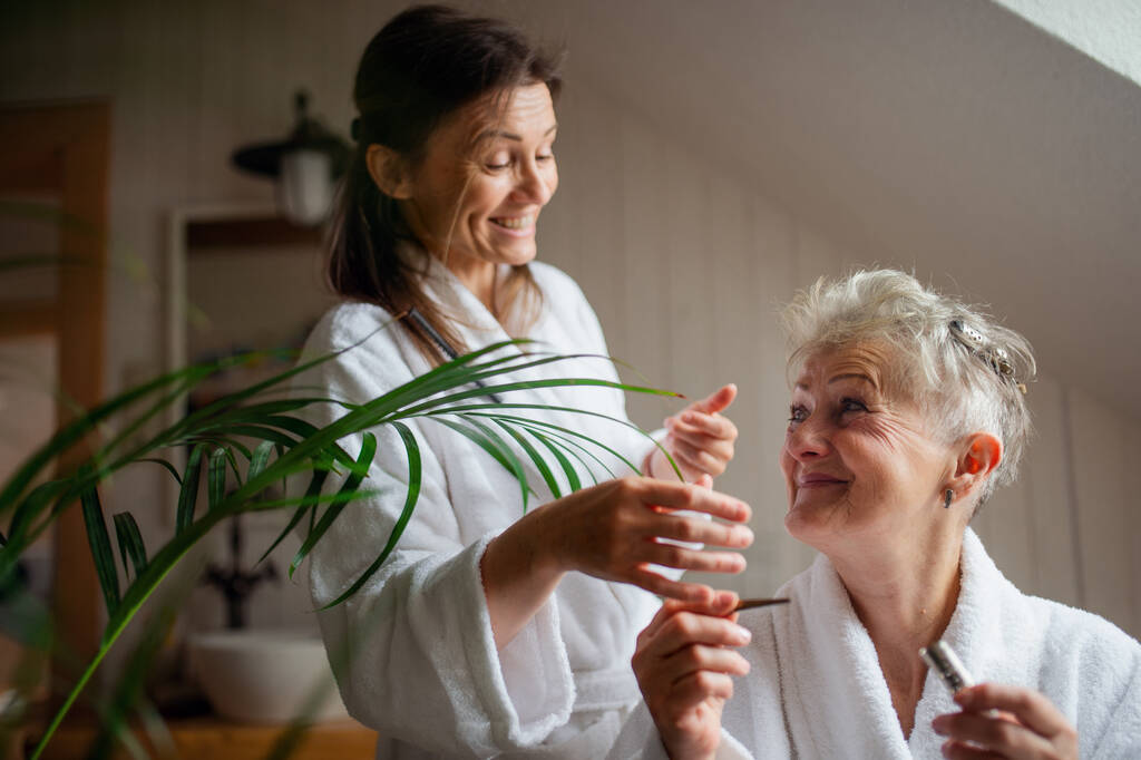 Glückliche Seniorin im Bademantel mit erwachsener Tochter zu Hause, Selfcare-Konzept. - Foto, Bild