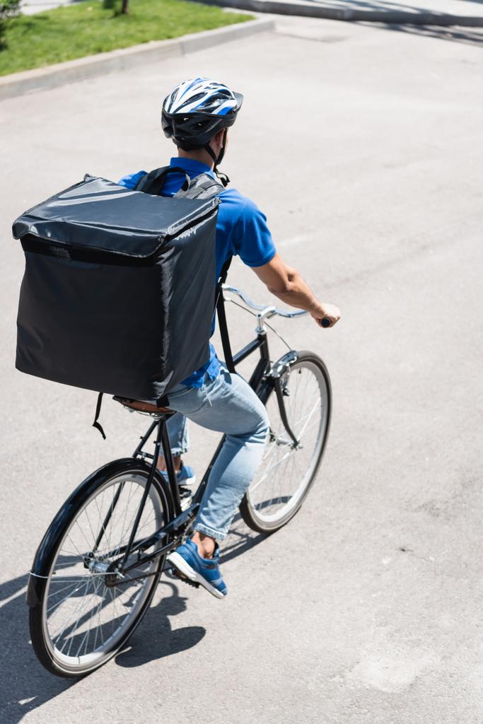 Młody dostawca z termo plecakiem jeżdżący na rowerze na zewnątrz  - Zdjęcie, obraz