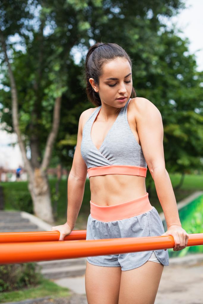 bonita mulher em sportswear exercitando em barras paralelas fora - Foto, Imagem
