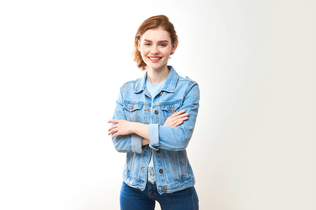 Retrato de una joven pelirroja sobre un fondo blanco aislado en jeans. Mira a la cámara. - Foto, imagen