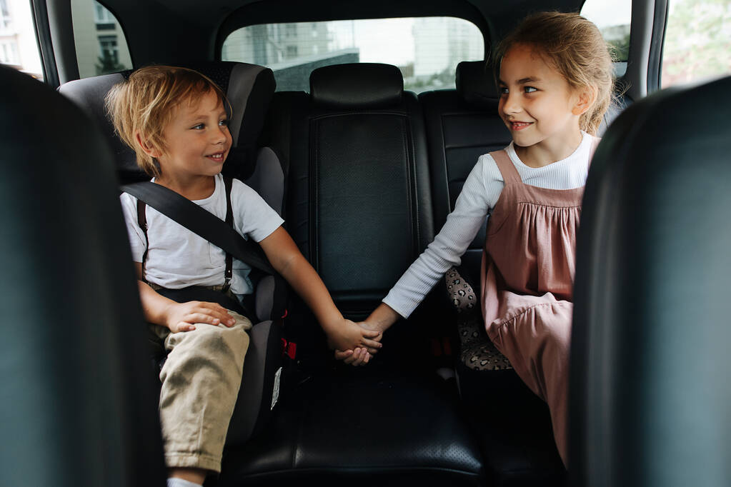 Dos hermanos cariñosos sentados en el asiento trasero de un coche, tomados de la mano, mirándose. Mostrando apoyo. - Foto, Imagen