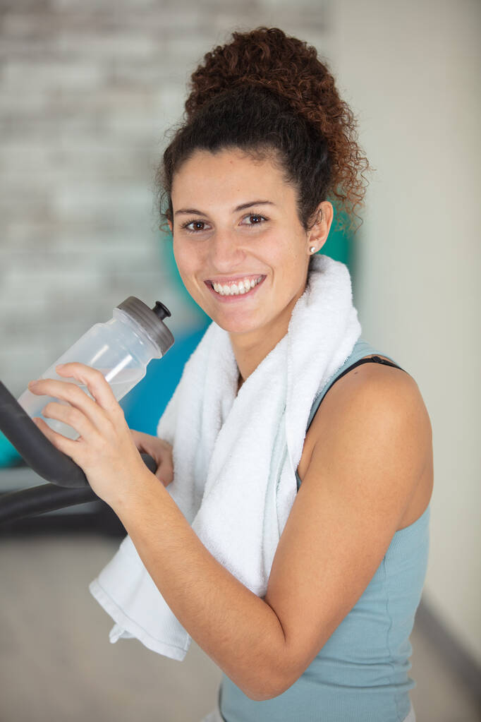zufriedenes Mädchen in einem Fitnessstudio mit einer Wasserflasche - Foto, Bild