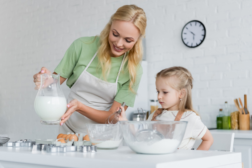 Mutter zeigt Tochter in Küche Krug mit Milch - Foto, Bild