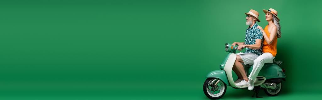 vidám, fajok közötti és középkorú pár napszemüvegben moped on green, banner - Fotó, kép