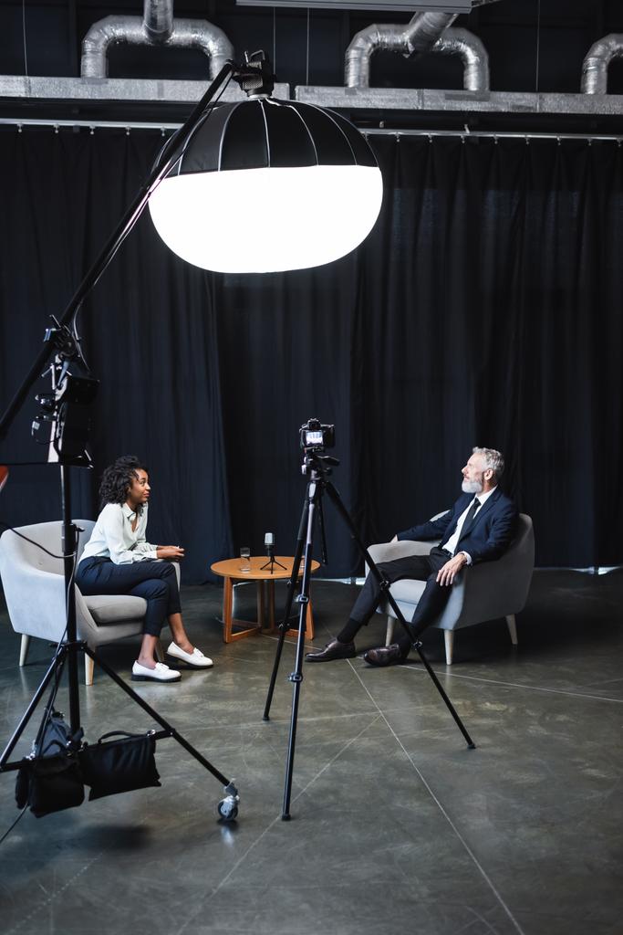 Afrikalı Amerikalı gazeteci iş adamıyla röportaj stüdyosunda konuşuyor.  - Fotoğraf, Görsel