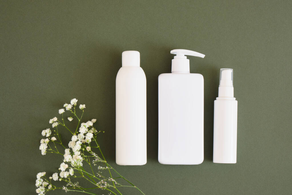 three different blank white bottles on a dark green background background, cosmetics mock-up Natural cosmetic packaging. mock up beauty product concept. - Photo, Image