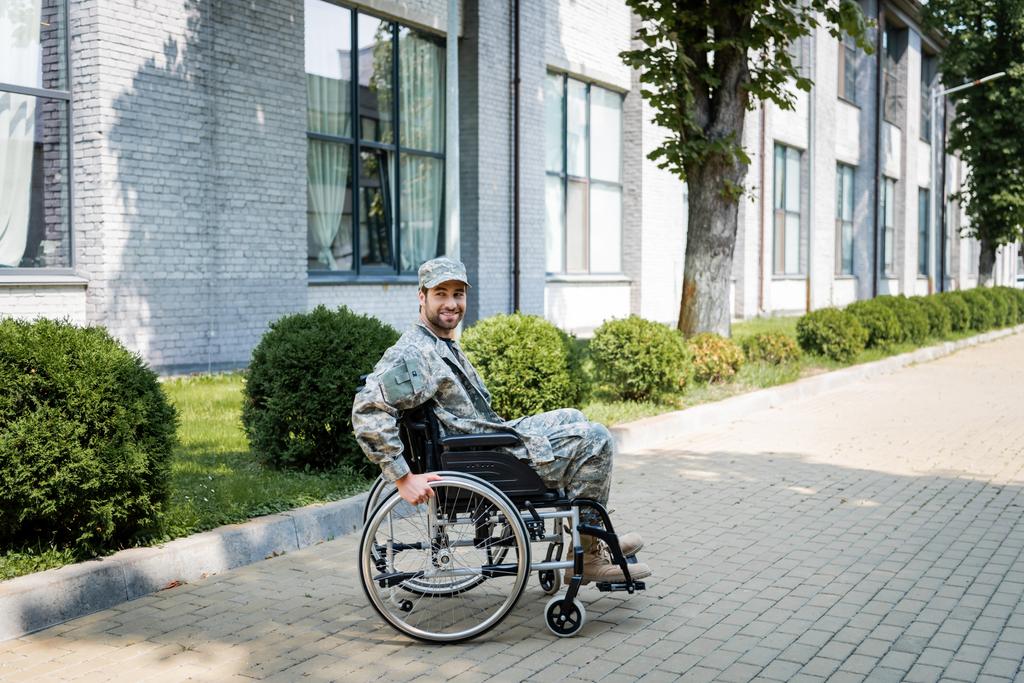 young handicapped veteran in wheelchair smiling on city street - Photo, Image