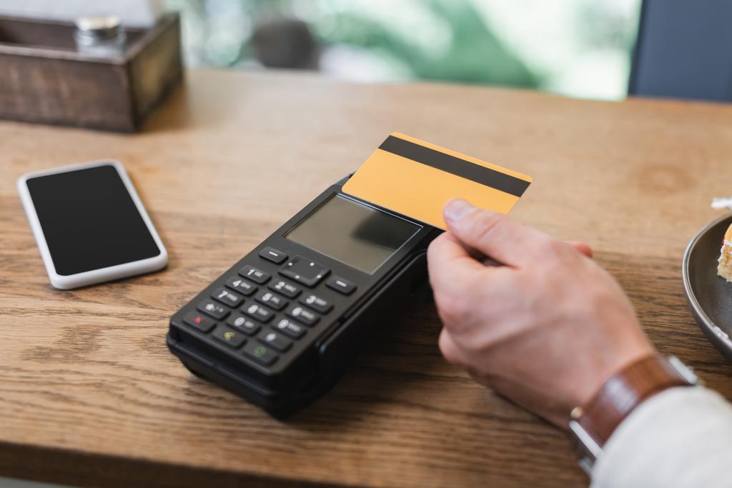 oříznutý pohled na zákazníka platícího kreditní kartou v kavárně  - Fotografie, Obrázek