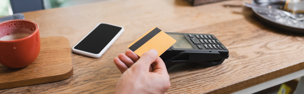 vágott kilátás a férfi fizet hitelkártyával közelében okostelefon kávézóban, banner - Fotó, kép