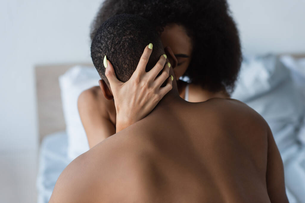 Hämärtynyt afrikkalainen amerikkalainen nainen suutelee paidaton poikaystävä makuuhuoneessa  - Valokuva, kuva
