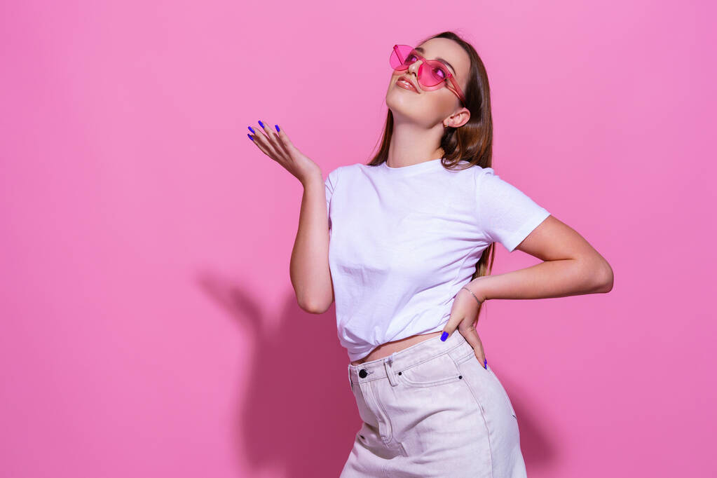 Jonge vrouw over geïsoleerde roze achtergrond met bril - Foto, afbeelding