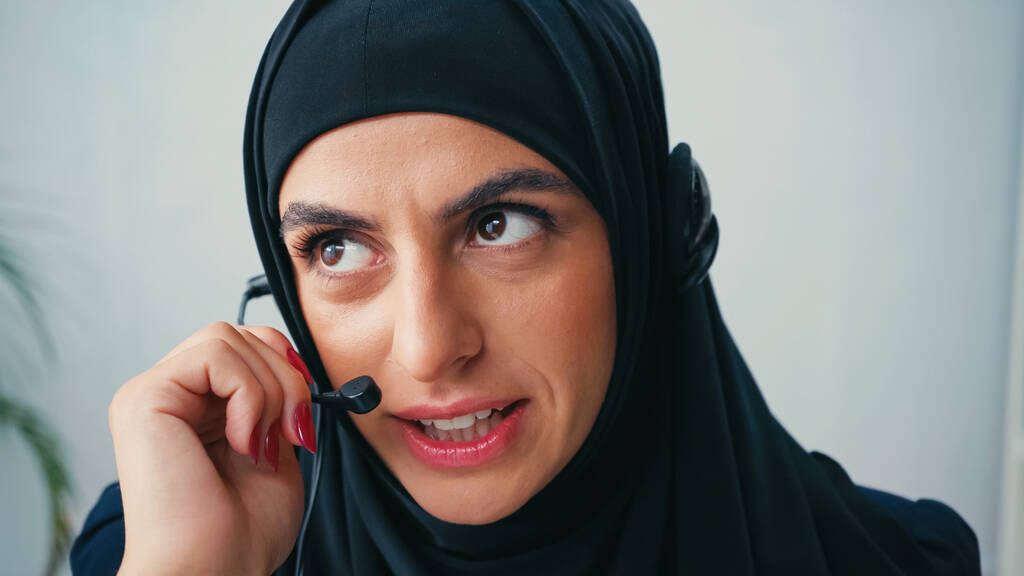 Başörtülü Müslüman kadın, çağrı merkezinde kulaklık kullanıyor ve konuşuyor.  - Fotoğraf, Görsel