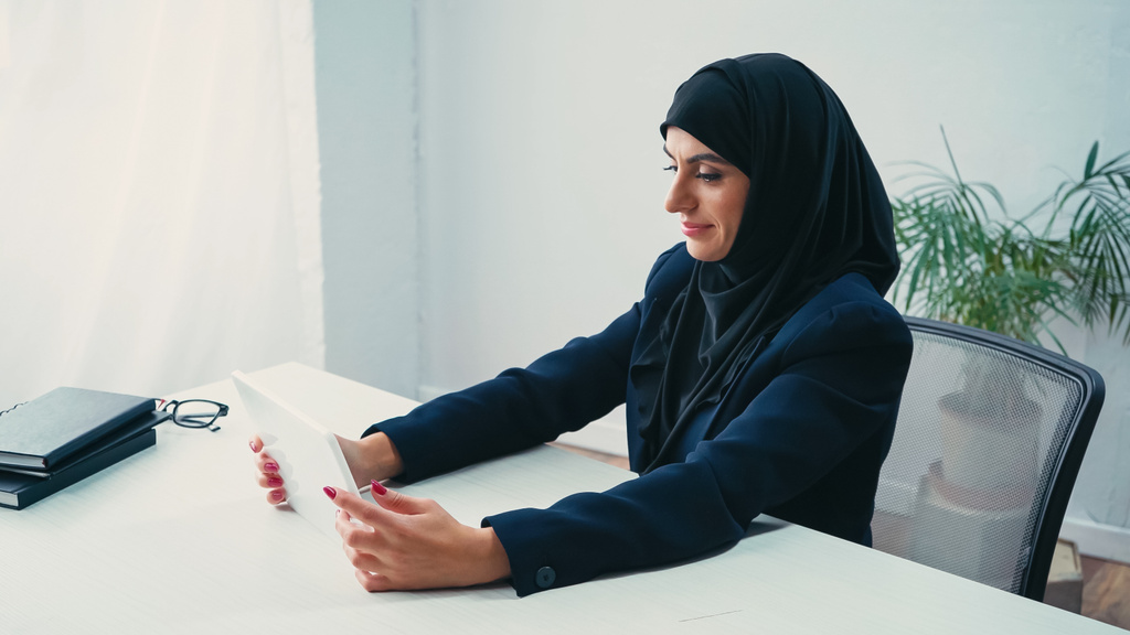 задоволена мусульманська бізнес-леді, використовуючи цифровий планшет в офісі
  - Фото, зображення