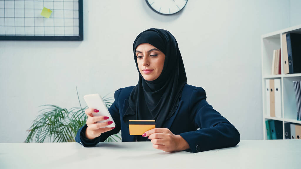 Мусульманка использует смартфон и кредитную карту во время покупок онлайн  - Фото, изображение