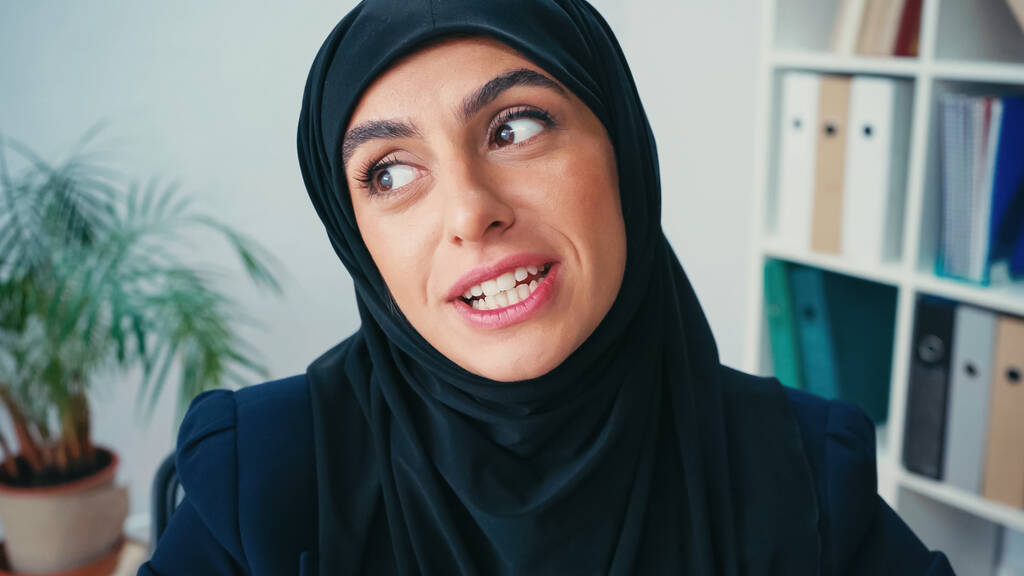молода мусульманська бізнес-леді в хіджабі розмовляє, дивлячись далеко
 - Фото, зображення
