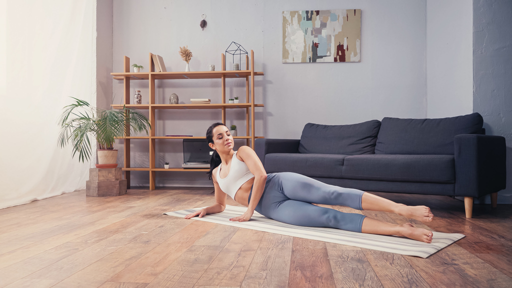 Csinos sportos nő edz otthon a fitnesz szőnyegen  - Fotó, kép