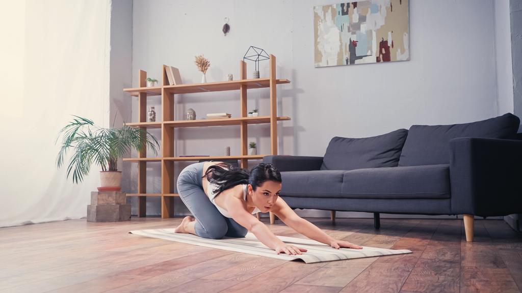 Mezítlábas sportnő nyújtózkodik vissza fitnessz szőnyegen otthon  - Fotó, kép