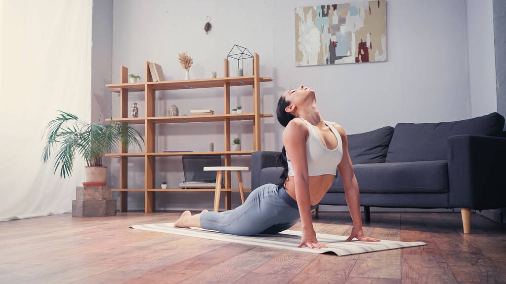 Jonge mooie sportvrouw stretching op fitness mat thuis  - Foto, afbeelding