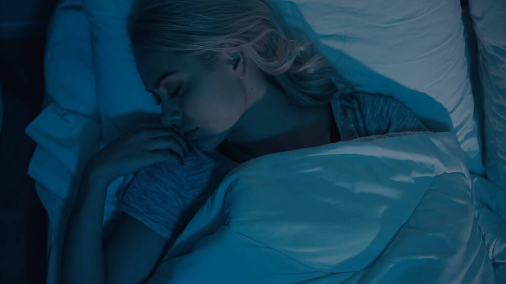 Vista superior de la mujer joven durmiendo en la cama por la noche  - Foto, imagen