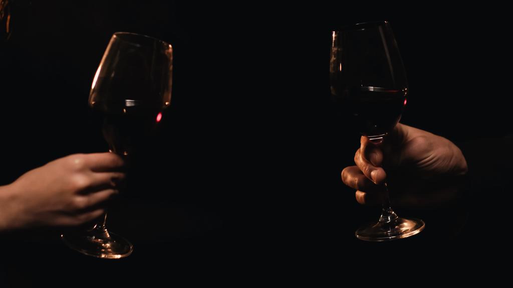 Обрізаний вид пари, що тримає окуляри з вином ізольовані на чорному
  - Фото, зображення