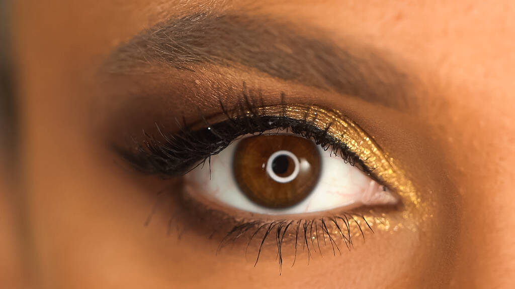 vista parcial de mujer afroamericana con ojo marrón y sombra de ojos brillante con brillo  - Foto, imagen