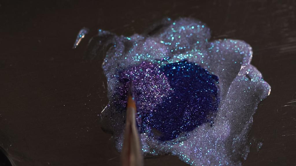 верхний вид кисти возле сверкающей фиолетовой жидкости с мерцанием  - Фото, изображение