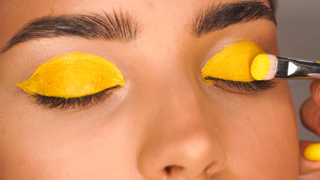 vágott kilátás nő alkalmazása sárga krémes szemhéjpúder kozmetikai kefe - Fotó, kép