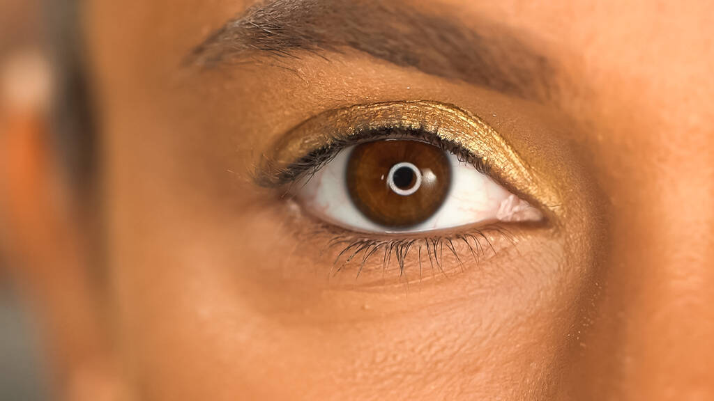 cropped view of african american woman with brown eye and golden eye shadow - Photo, Image