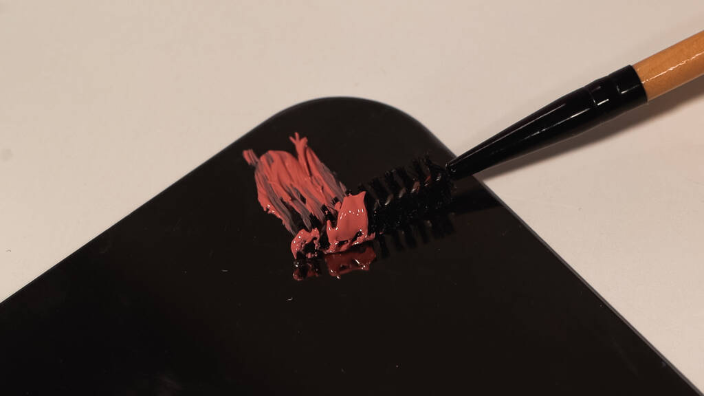 černý řasenka štětec v blízkosti růžové lesklé kapaliny na bílém povrchu - Fotografie, Obrázek