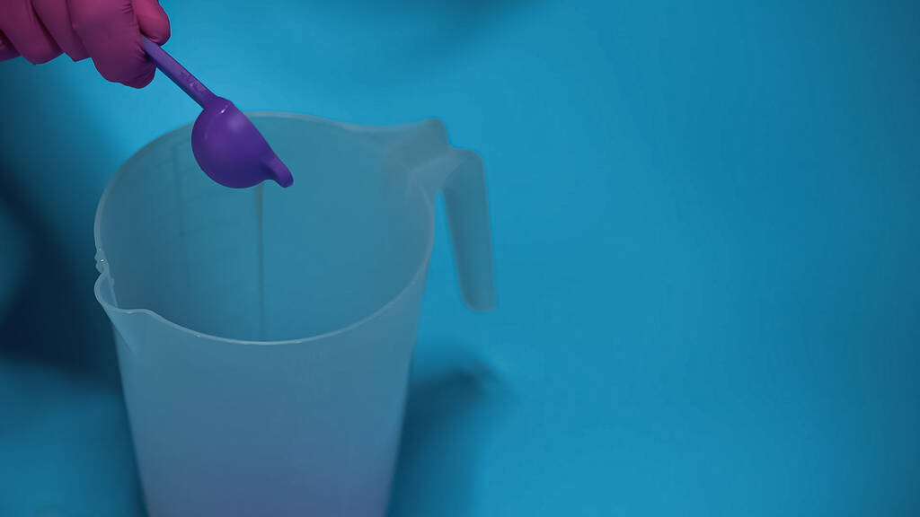 обрезанный вид человека, наливающего жидкость в пластиковый кувшин на синий - Фото, изображение