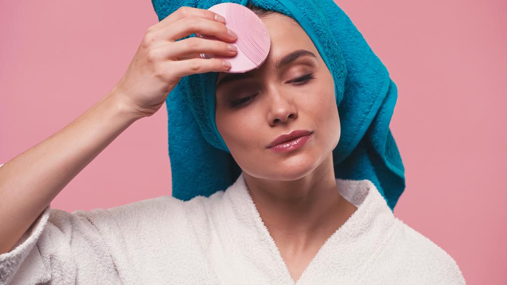 giovane donna che utilizza detergente elettrico in silicone sul viso isolato su rosa - Foto, immagini