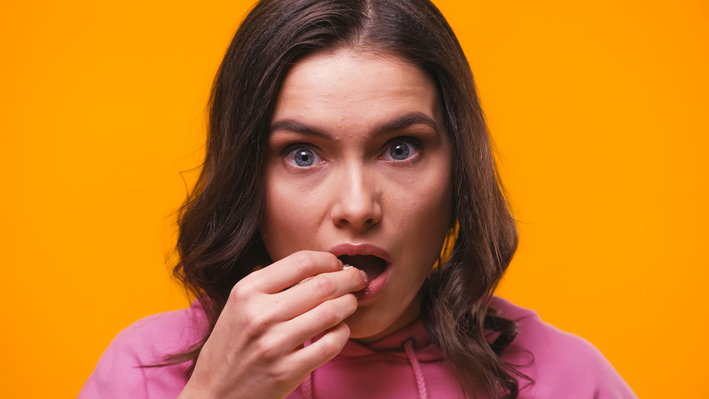 mulher chocada comer pipocas enquanto assiste filme de tirar o fôlego isolado no amarelo - Foto, Imagem
