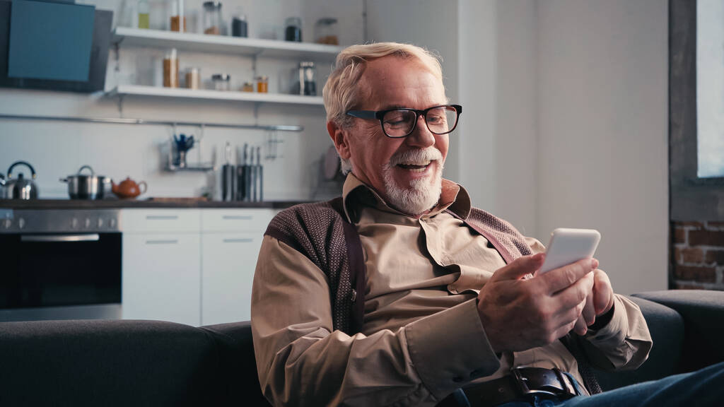 boldog idősebb férfi szemüvegben üzenetküldés mobilon otthon - Fotó, kép