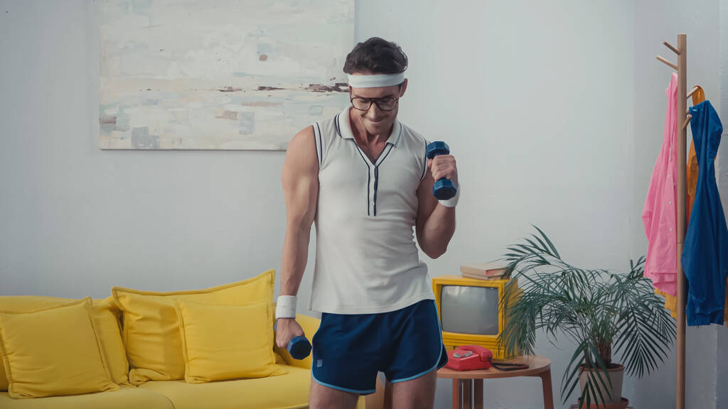 sportoló szemüvegben súlyemelés a nappaliban, retro sport koncepció - Fotó, kép