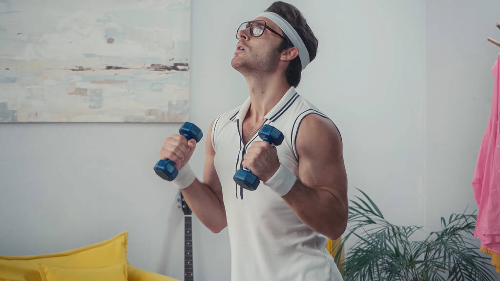 спортсмен в очках, поднимающий гантели, концепция ретро спорта - Фото, изображение