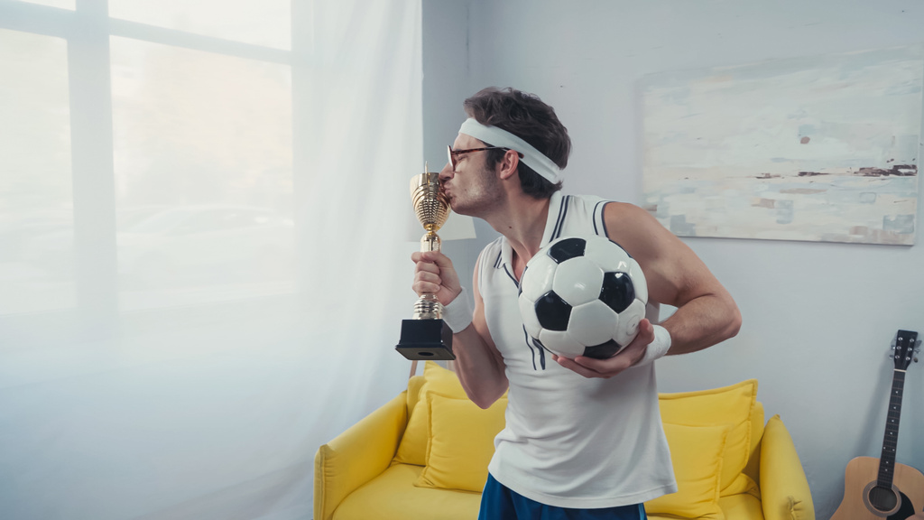jugador de fútbol besos copa trofeo de oro y celebración de pelota de fútbol - Foto, Imagen