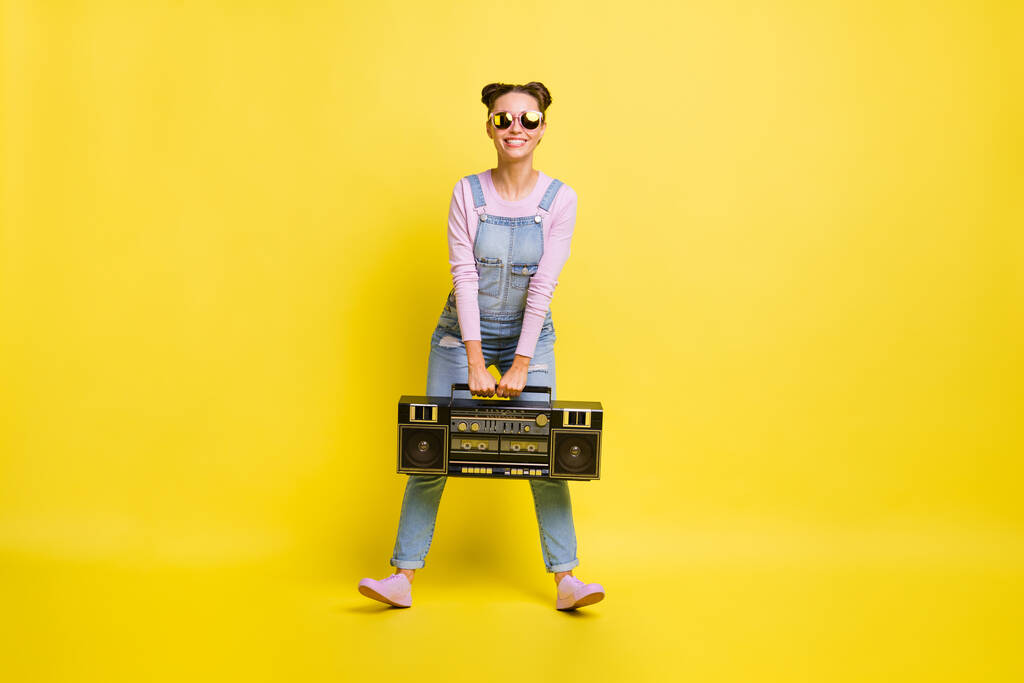 Plná velikost fotografie okouzlující veselá mladá žena držet boombox úsměv nosit brýle izolované na žlutém pozadí - Fotografie, Obrázek