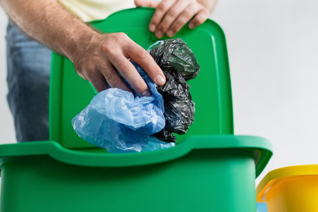 Gewassen beeld van wazig man houden plastic zakken in de buurt van prullenbak thuis  - Foto, afbeelding