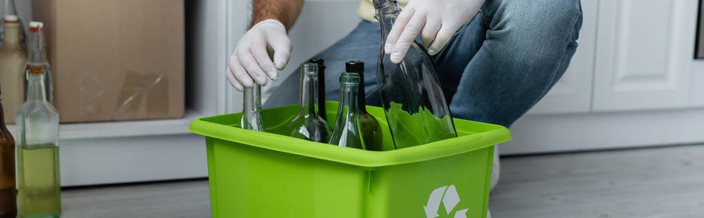 Vue recadrée de l'homme en gants de latex tenant bouteille près de la boîte avec panneau de recyclage, bannière  - Photo, image