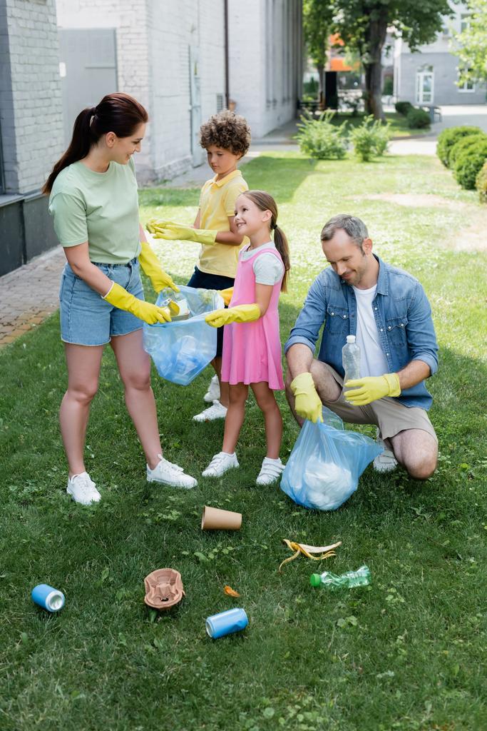 Pais positivos com crianças coletando lixo no gramado  - Foto, Imagem