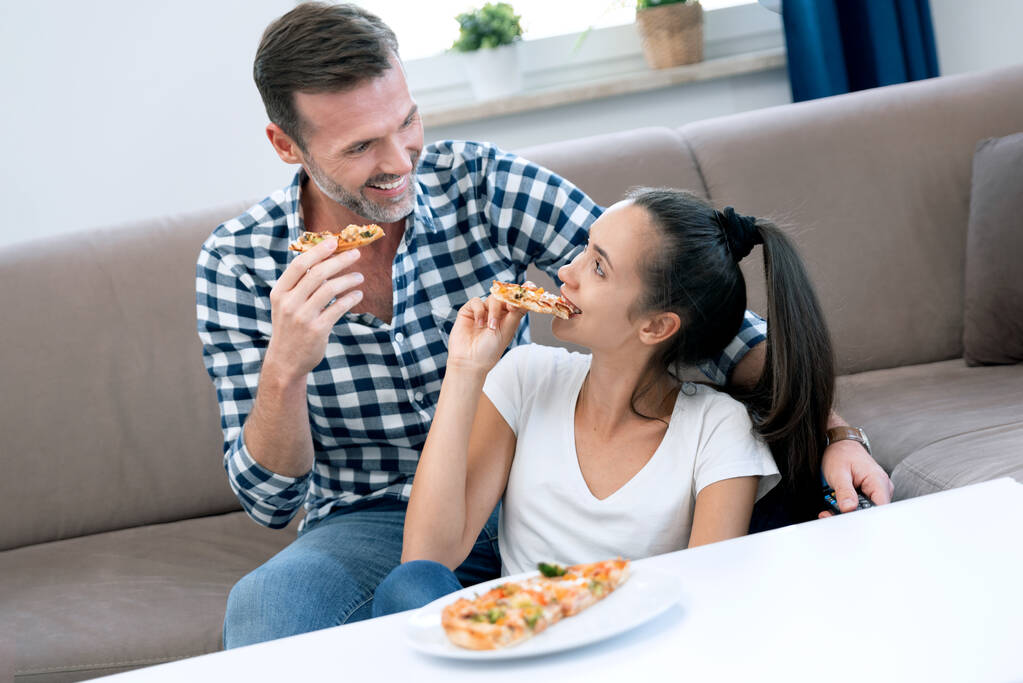 Paar beim Pizzaessen vor dem Fernseher. Freizeit zu Hause verbringen - Foto, Bild