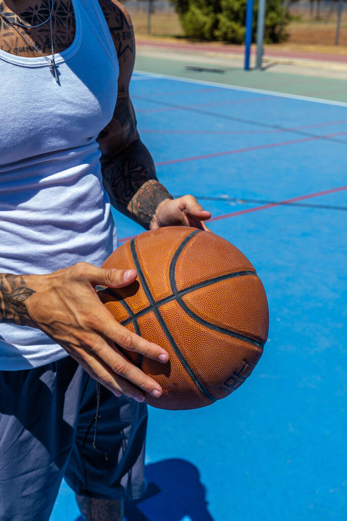 Вертикальний кидок спортивного кавказького чоловіка, який тримає баскетбольний м'яч. - Фото, зображення