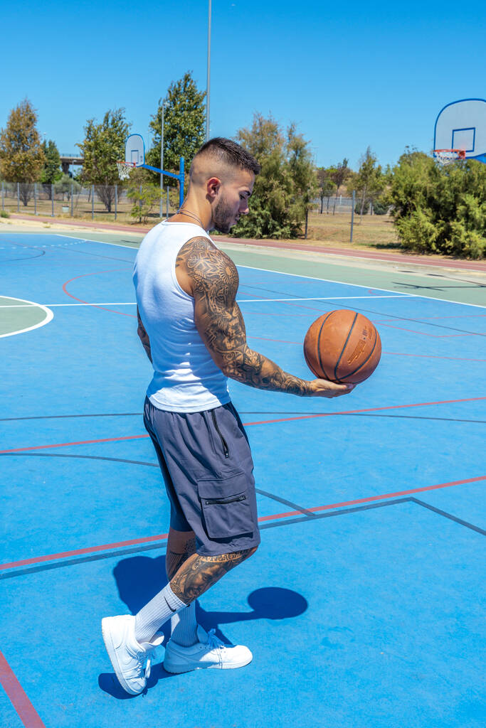 Um tiro vertical de um homem caucasiano esportivo com tatuagens jogando basquete - Foto, Imagem