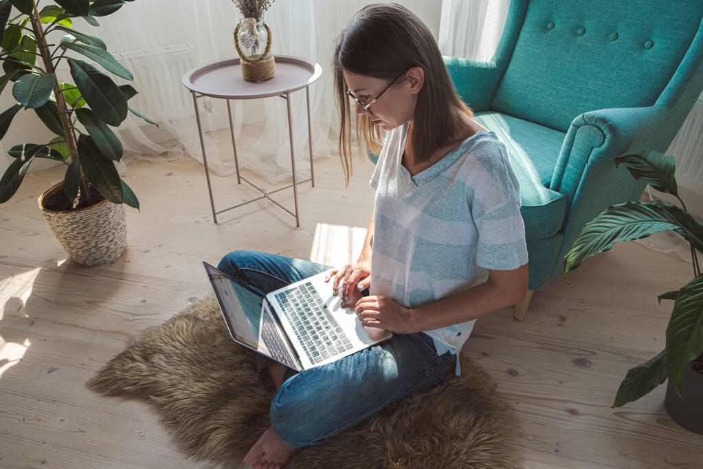 Junge Frau mit Laptop zur Arbeit, zu Hause auf dem Boden sitzend. Flexible Arbeitszeiten und Fernarbeit - Foto, Bild