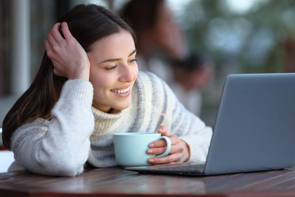 Boldog nő nézi média tartalmát laptop ül egy kávézóban télen - Fotó, kép