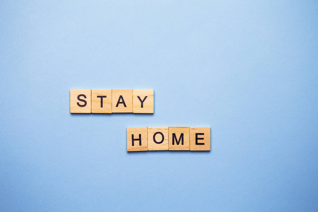 Letras decorativas de madeira formando a palavra ficar em casa em um fundo branco, vista superior - Foto, Imagem