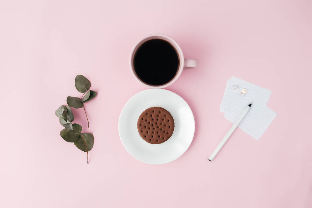 Conceito de dia internacional da mulher, xícara de café, prato, biscoito, ramo, notas, caneta, folhas de eucalipto no fundo rosa. Foto de alta qualidade - Foto, Imagem