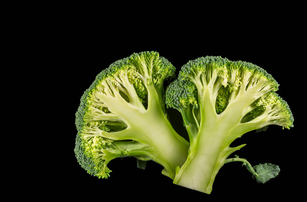 Broccoli roosjes in tweeën gesneden op een zwarte achtergrond - Foto, afbeelding